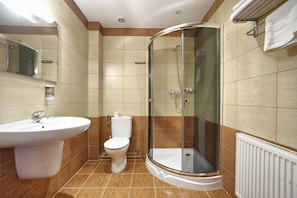 Un baño con lavamanos, inodoro y ducha con mampara de vidrio.