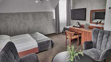 A hotel room with two beds, a desk with a chair, a TV, and a small table with a plant.