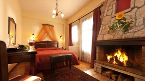 A room with a bed, a desk, a chair, a fireplace, and a window with curtains. - Fretzato Traditional Guest House (Pyli)