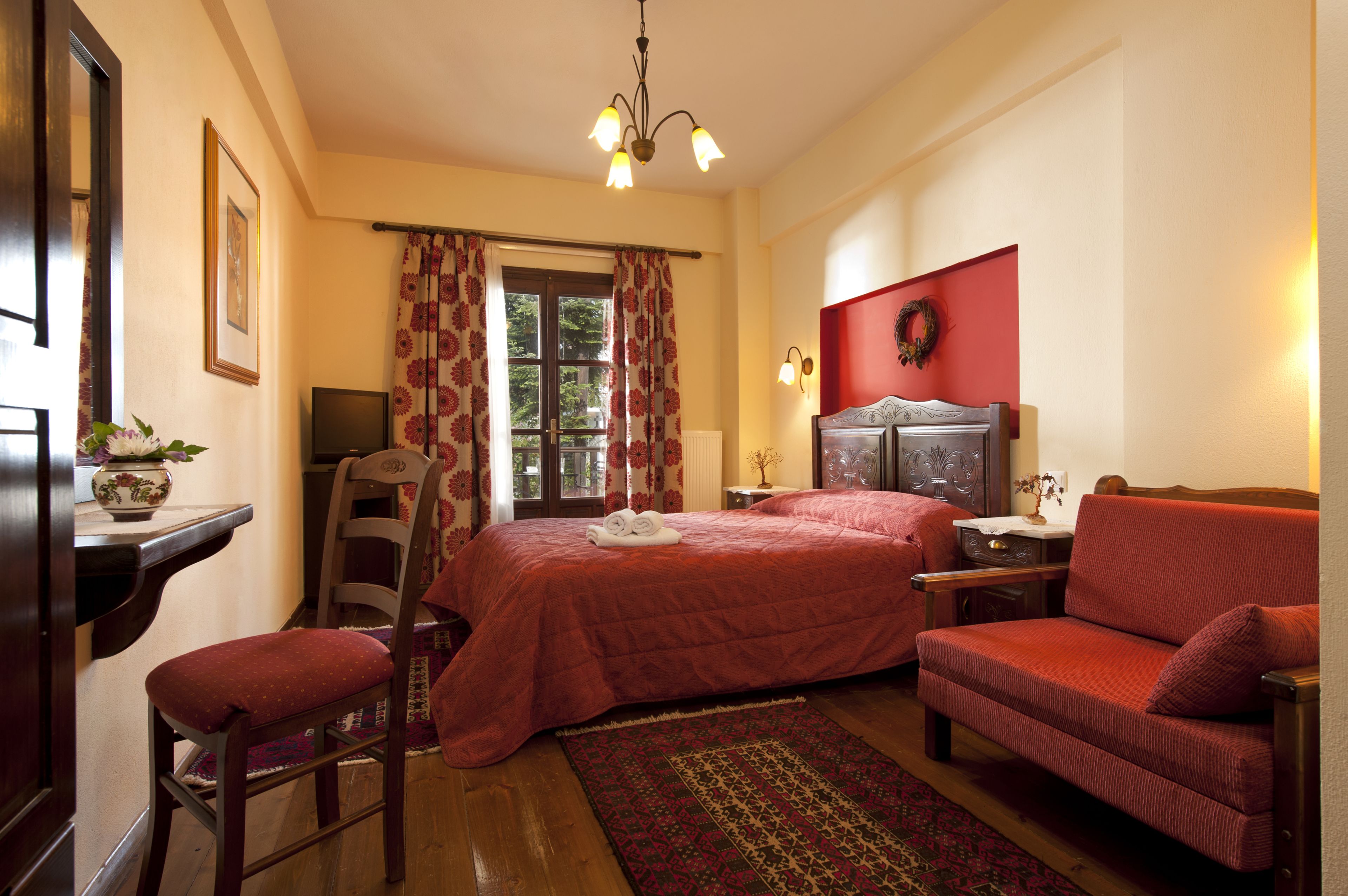 A hotel room with a bed, a chair, a desk, a television, and a window with curtains.