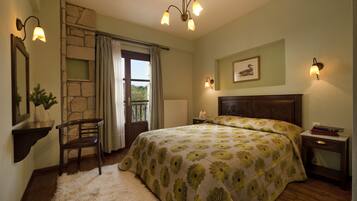 Un dormitorio con una cama grande, un muro de piedra decorativo, una mesita de noche de madera, una silla y una ventana con cortinas.