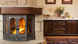 A stone fireplace with a fire, wooden cabinets, and a rug on the floor. - Fretzato Traditional Guest House (Pyli)