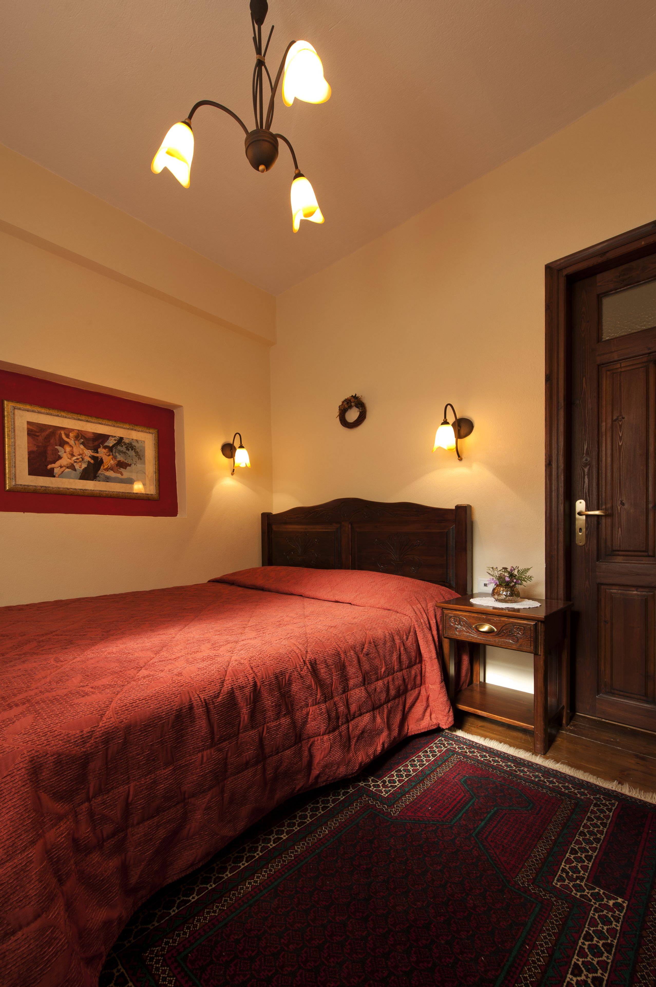 Un dormitorio con cama, mesita de noche, luz empotrada en la pared y una puerta.