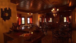 A cozy restaurant with wooden interiors, a bar area, and a dining space with multiple tables and chairs. - Kroupi Hotel (Pyli)