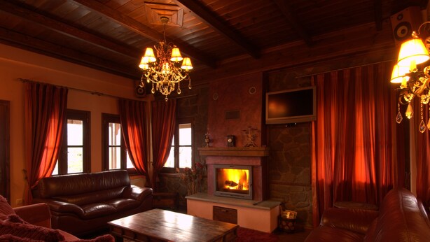 A cozy living room with a fireplace, leather sofas, and a chandelier. - Kroupi Hotel (Pyli)