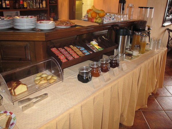 Un bufé con diferentes opciones de comida, incluyendo pasteles, frutas y salsas.
