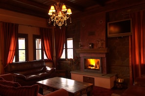 Una sala de estar acogedora con chimenea, sofá de cuero y candelabro.