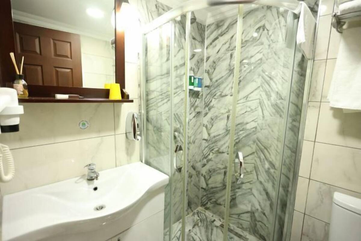 A bathroom with a glass-enclosed shower, a sink, and a mirror.