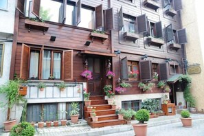 A multi-story building with wooden balconies, potted plants, and a staircase leading to the entrance. - Asmali Hotel (Istanbul)