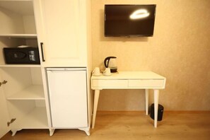 A room with a white cabinet, a small white table with a kettle, a black radio, and a mounted television. - Asmali Hotel (Istanbul)