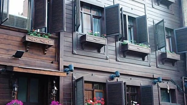 Edifici d'amb diverses plantes amb façana de fusta, múltiples balcons amb jardineres i finestres amb persianes.