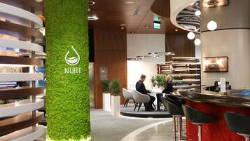 A modern bar area with a green wall, bar stools, and a counter.