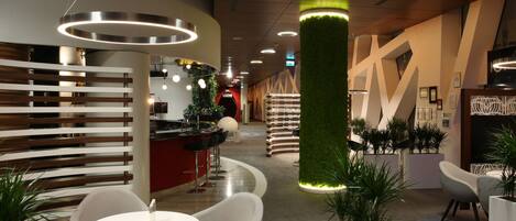 A modern lobby with a reception desk, seating area, and decorative lighting.