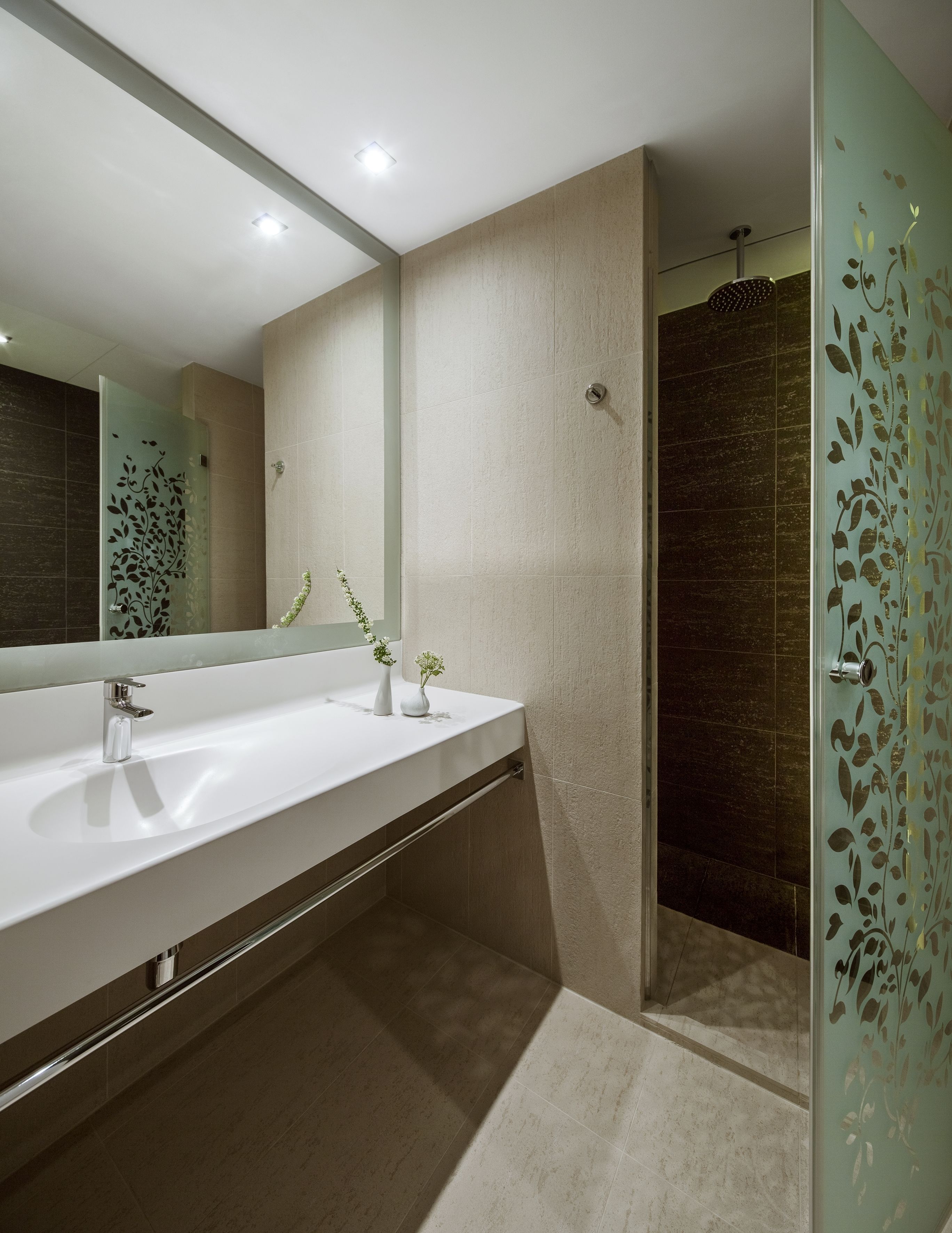 Un baño moderno con un espejo grande, dos lavamanos y una zona de ducha.