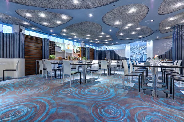 Un comedor moderno con alfombra estampada, mobiliario contemporáneo y un diseño de techo original.