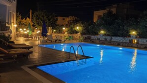 A swimming pool with lounge chairs and umbrellas, surrounded by stone walls and greenery. - Karaburun Konak Hotel (Karaburun)