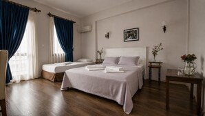 A hotel room with a large bed, a smaller bed, a sitting area, and a window with curtains. - Karaburun Konak Hotel (Karaburun)