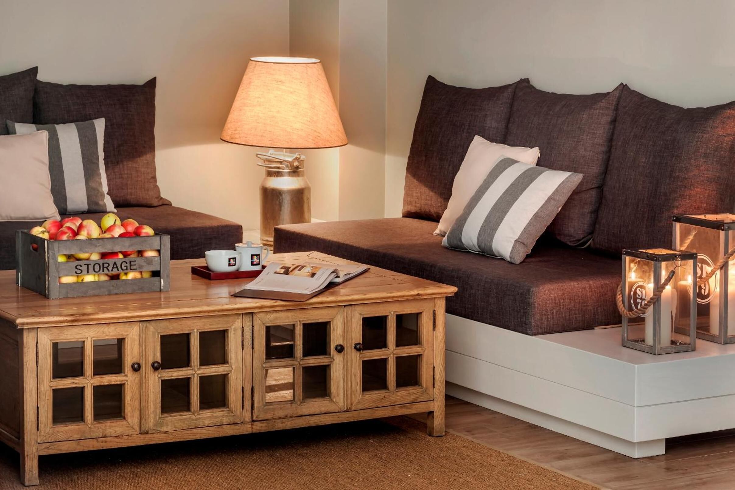A cozy living room with a sofa, a wooden coffee table with storage, a lamp, and decorative lanterns.