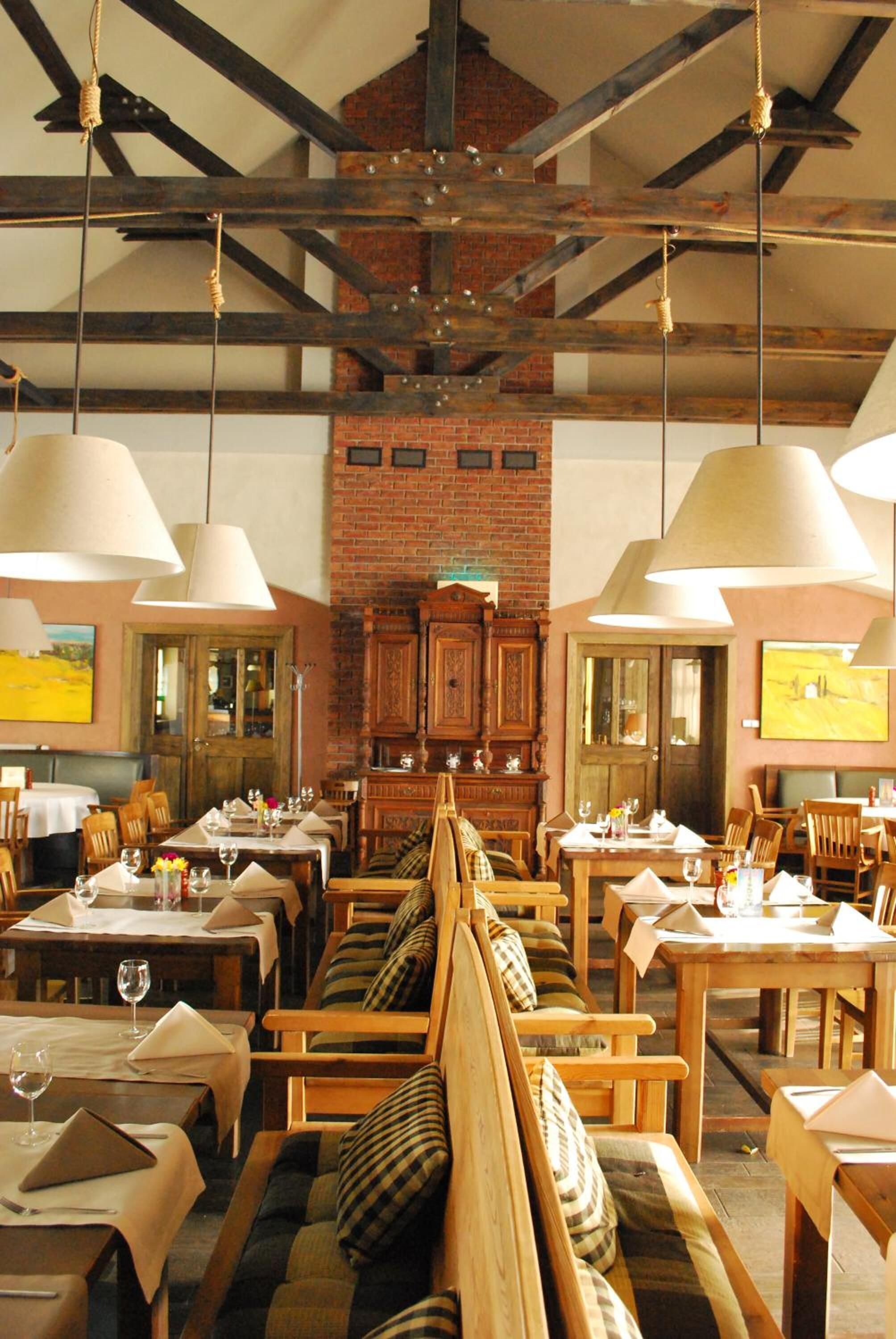 Un restaurante con mesas y bancos de madera, lámparas colgantes y paredes de ladrillo.