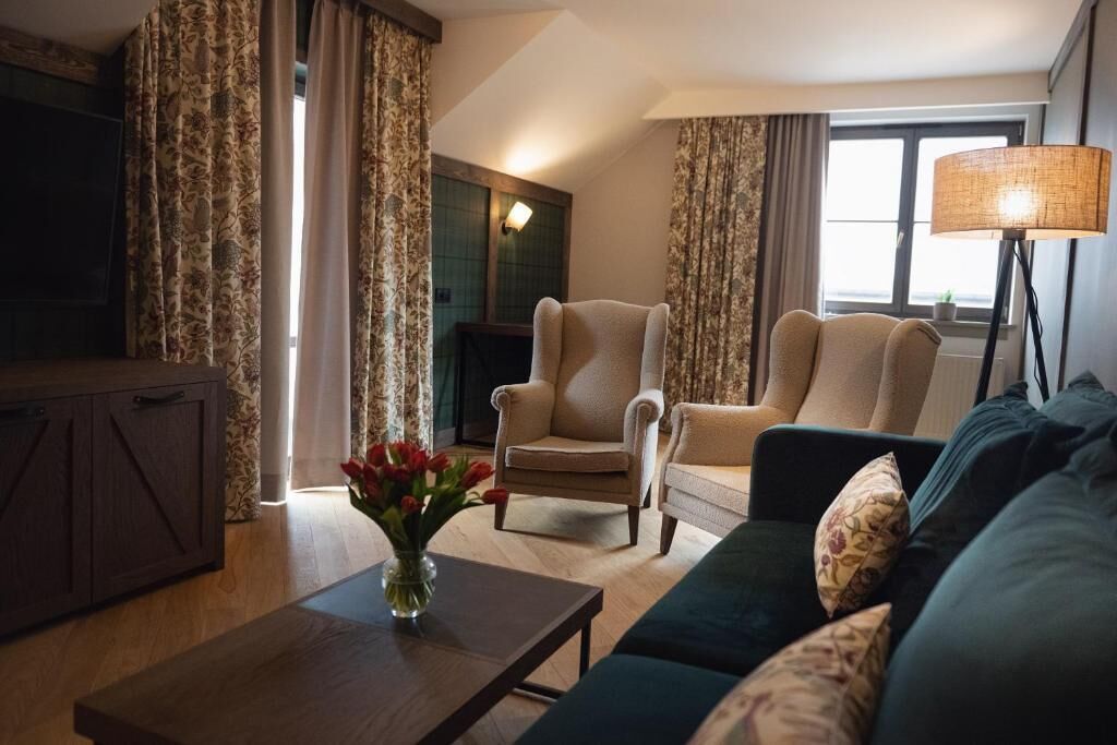 A living room with a sofa, armchairs, a coffee table, and a lamp.