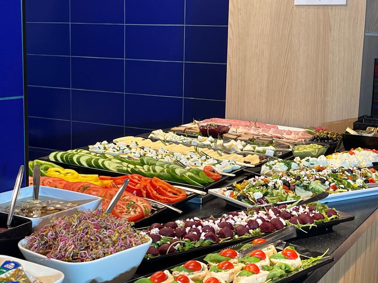 A buffet with various food items including salads, cheeses, and meats.