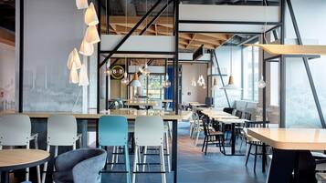 Een modern café met verschillende zitmogelijkheden, zoals tafels en stoelen, een bar en hanglampen.