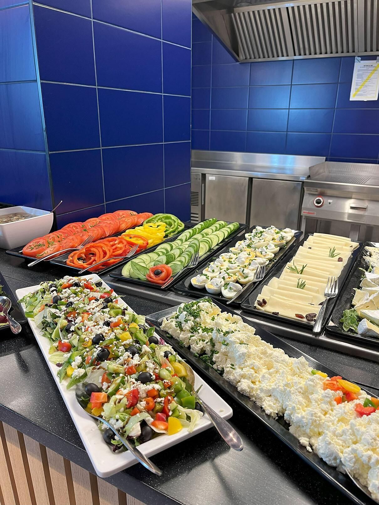Un bufé con diversos platos, incluyendo ensaladas, verduras y tablas de queso.