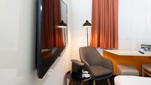 Een hotelkamer met een bed, een bureau, een stoel, een televisie en een lamp.