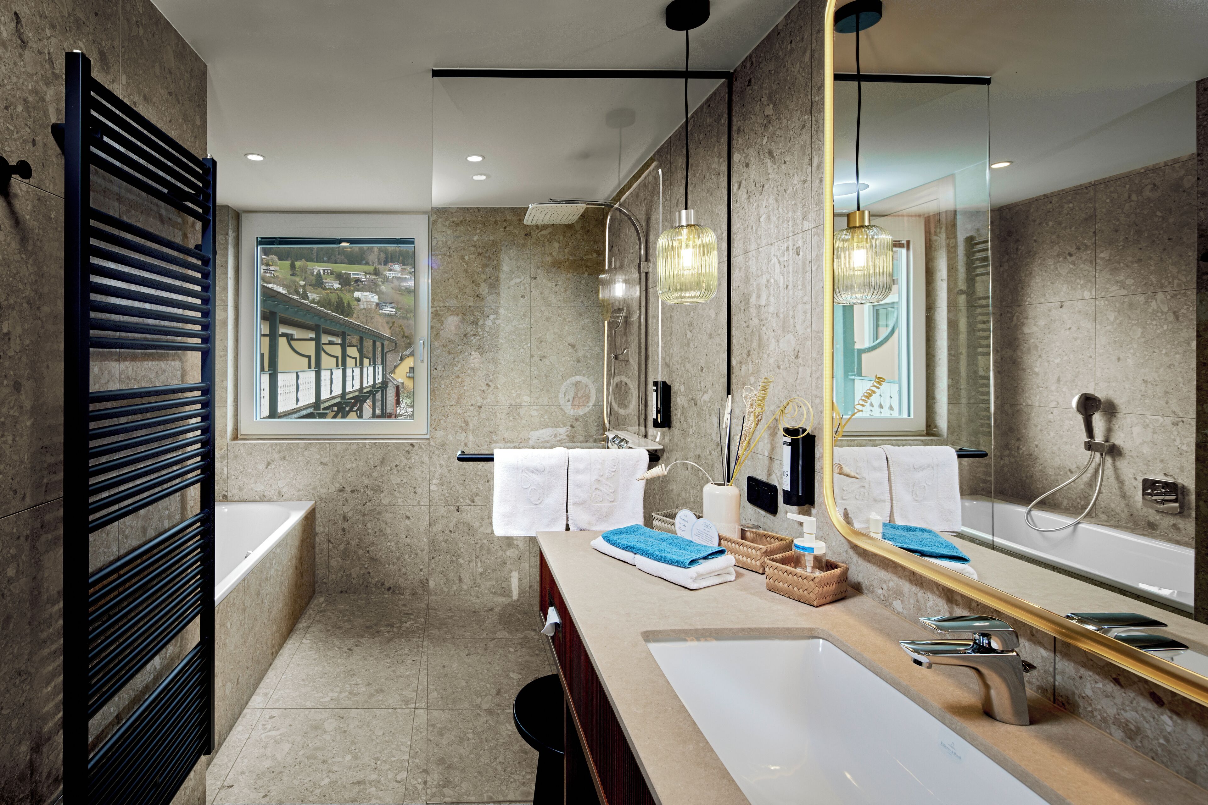 A modern bathroom with a large mirror, a bathtub, and a shower. There is a window providing a view of the outside.