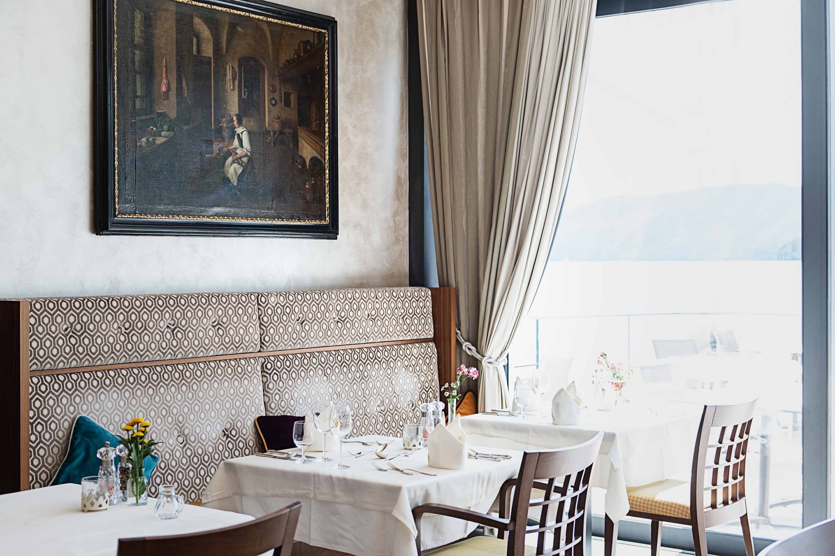 A dining area with a patterned headboard, a painting above the table, and a view of the outdoors.