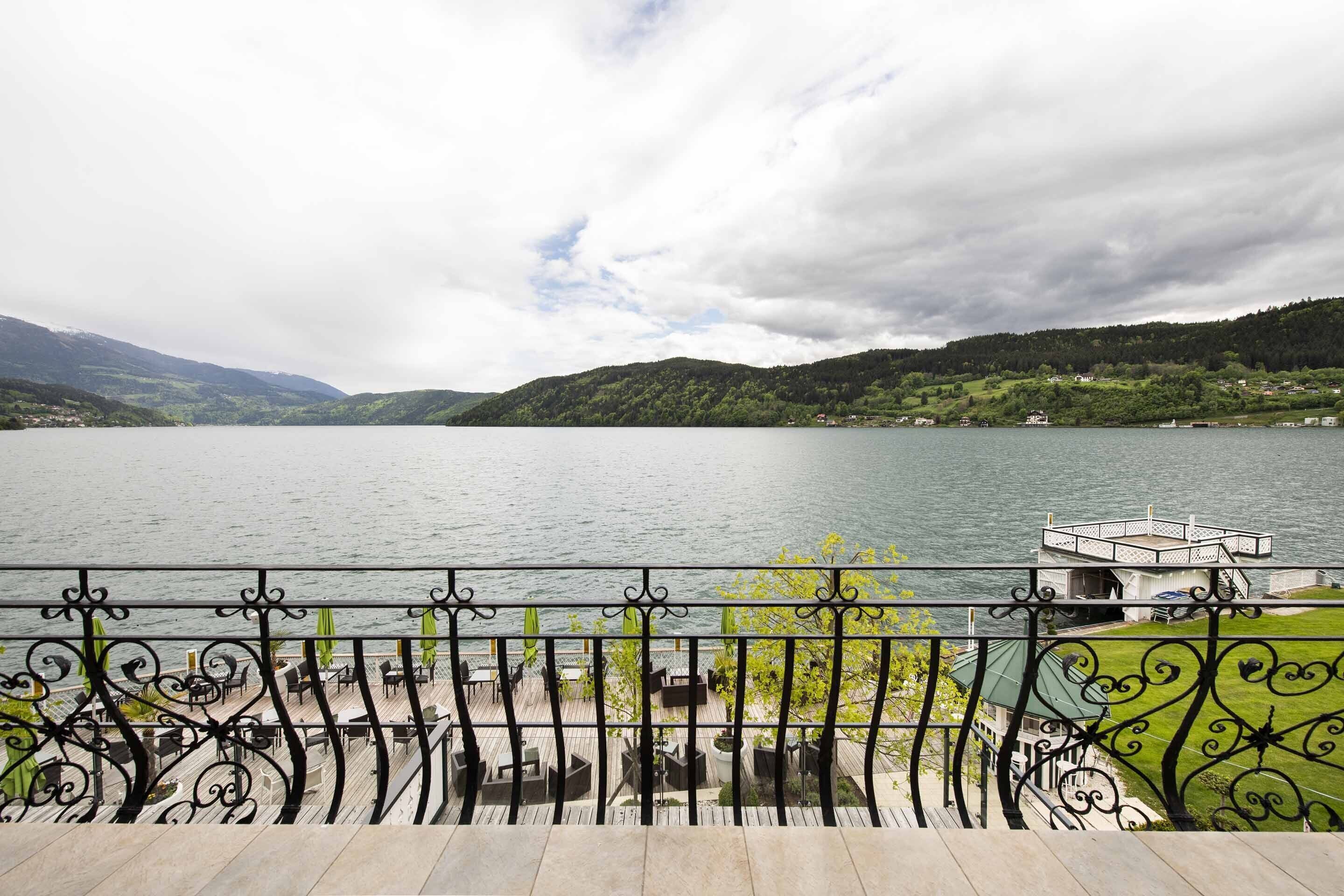 Un balcón frente al lago con mobiliario exterior y vistas al lago y las colinas circundantes.