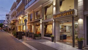 A hotel with a modern facade, outdoor seating, and a visible reception area. - Hotel Nefeli (Volos)