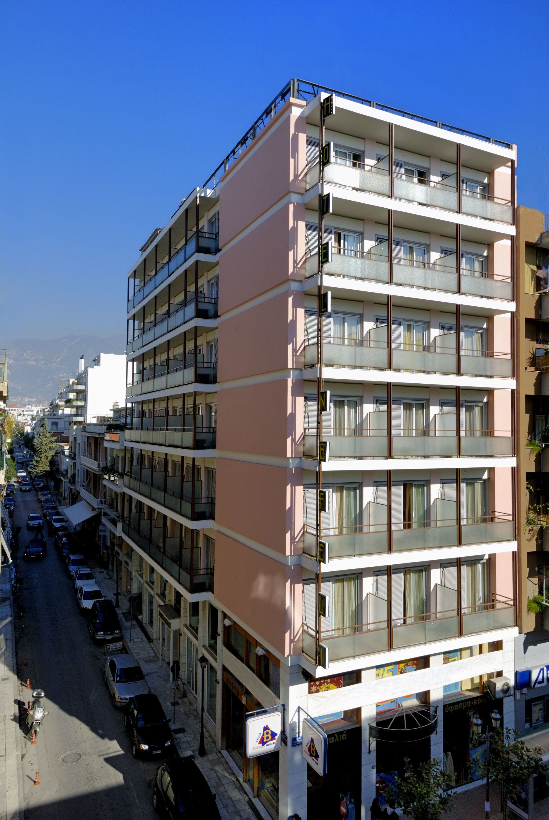 A multi-story building with balconies and a ground floor with shops.