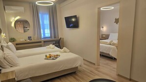 A modern hotel room with two beds, a TV, a mirror, a small table with breakfast, and a view of the city. - Hotel Nefeli (Volos)