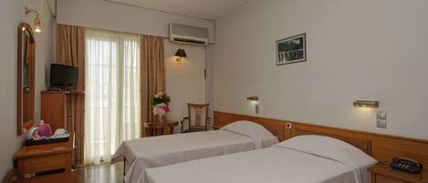 A hotel room with two beds, a desk, a chair, a television, and a picture on the wall.