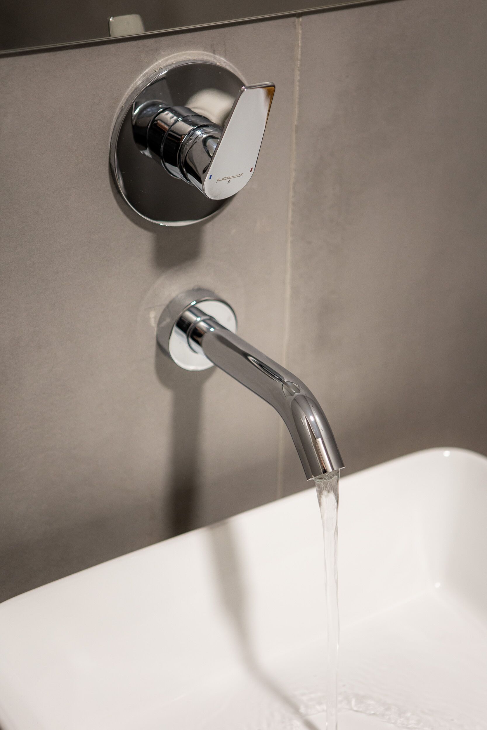 Un baño moderno con grifo cromado y lavamanos blanco.