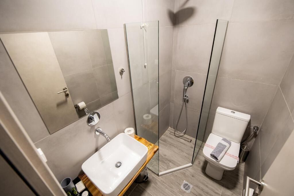 A modern bathroom with a glass shower enclosure, a sink, and a toilet.