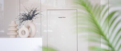 A modern room with a marble countertop, a vase with dried flowers, and a sign indicating the luggage room.