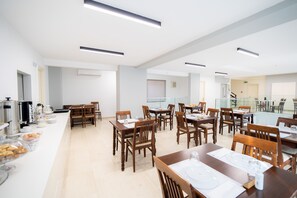 Enjoy meals in this stylish dining area, featuring wooden tables and a buffet counter with a variety of food options.