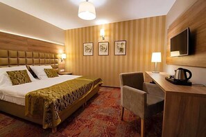 Habitación de hotel con una cama grande, un escritorio con silla, televisor y cuadros en la pared.