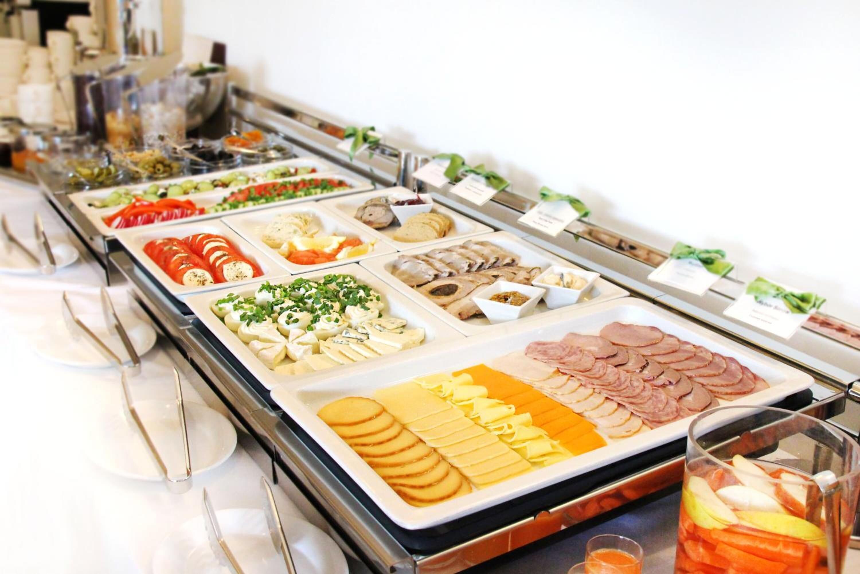 A buffet with various food items including sliced meats, cheeses, and vegetables.