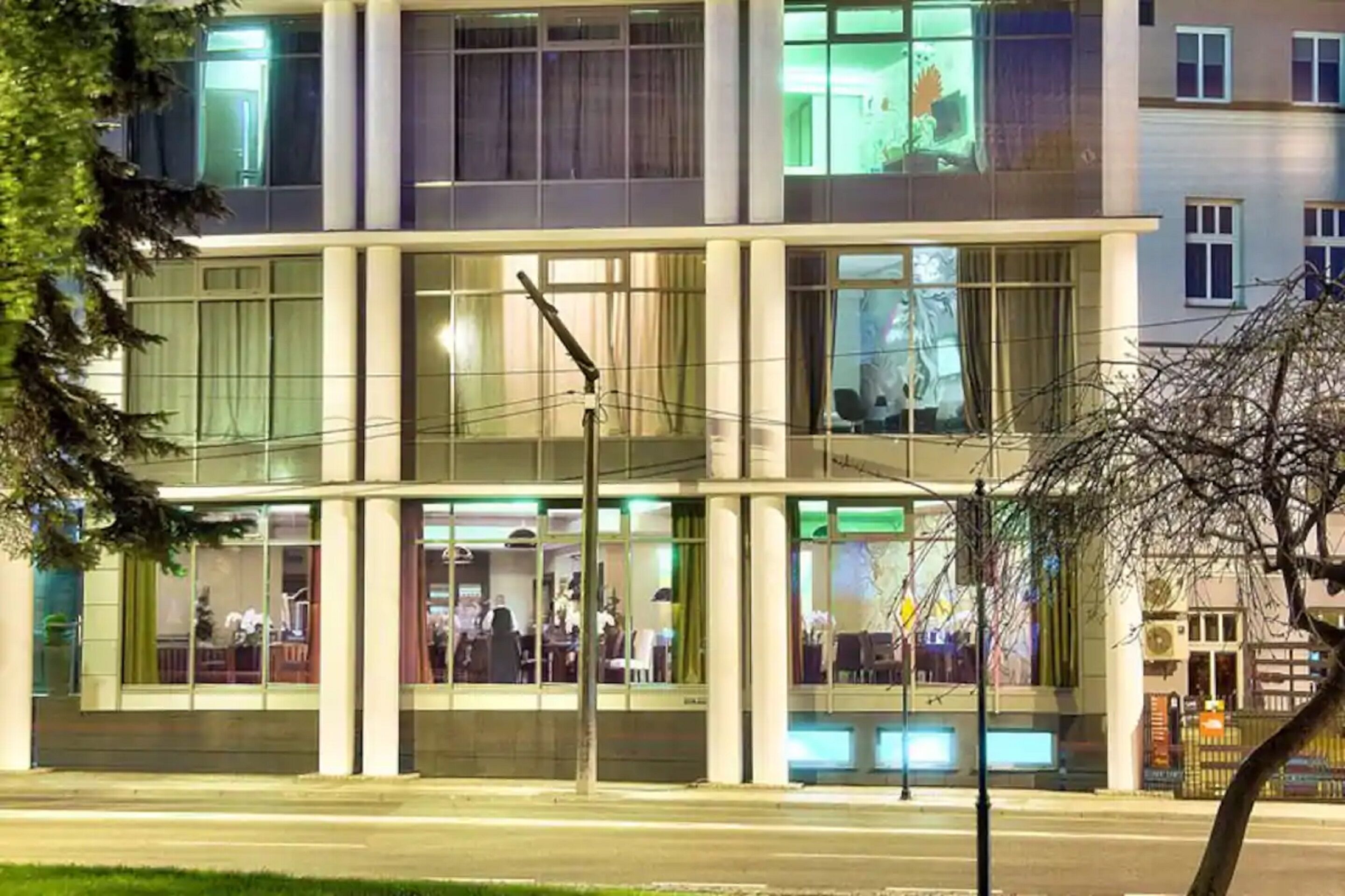 A modern building with multiple floors, large windows, and a visible restaurant or dining area on the ground floor.