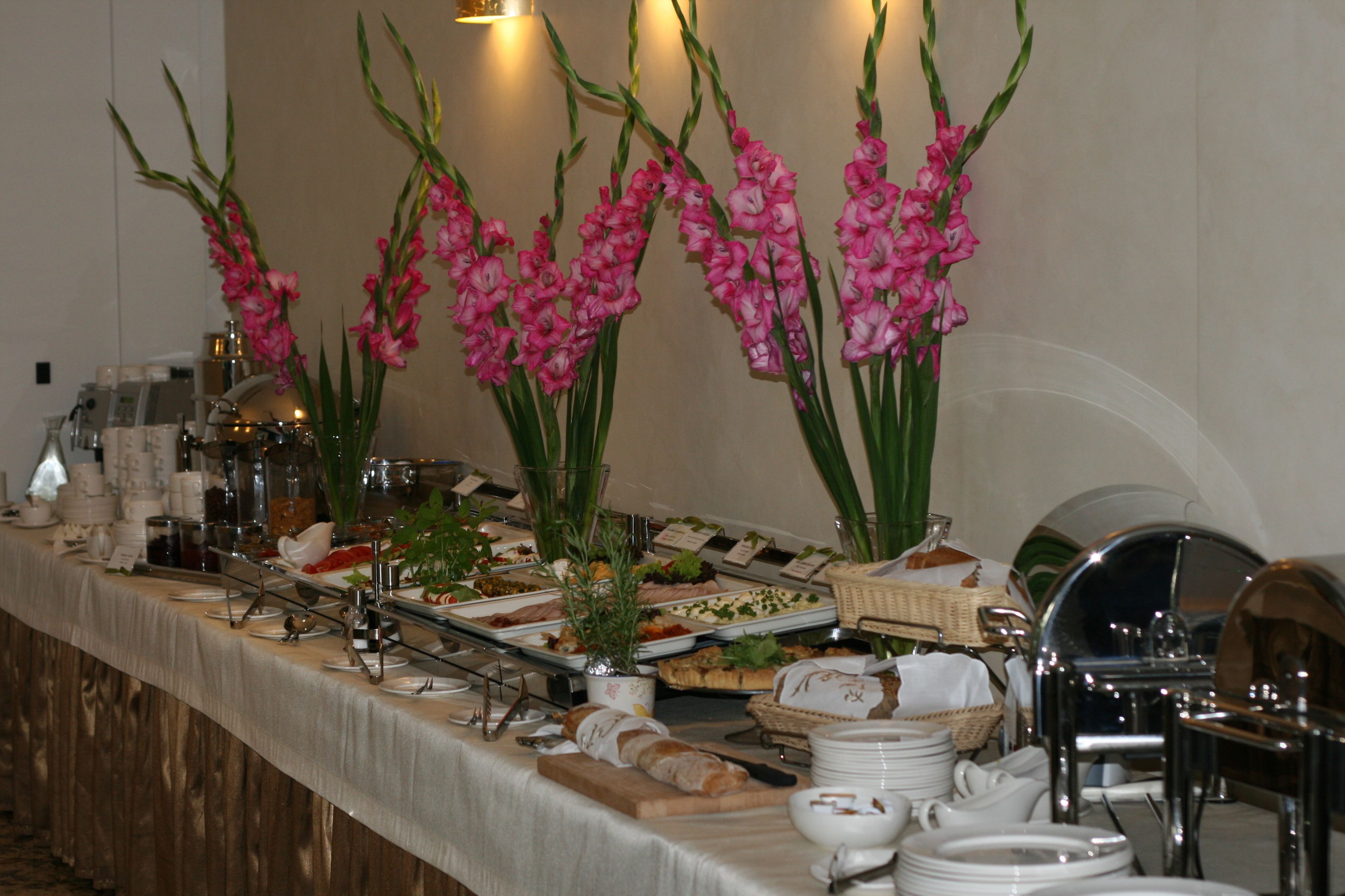 A buffet setup with various food items, including bread, salads, and desserts, arranged on a table with a long tablecloth.