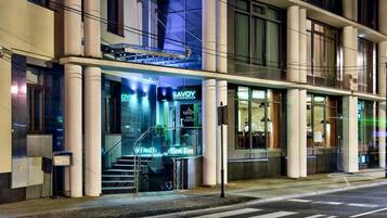 A modern building with a glass facade, a visible entrance with steps, and signage for 'Savoy Restaurante'.