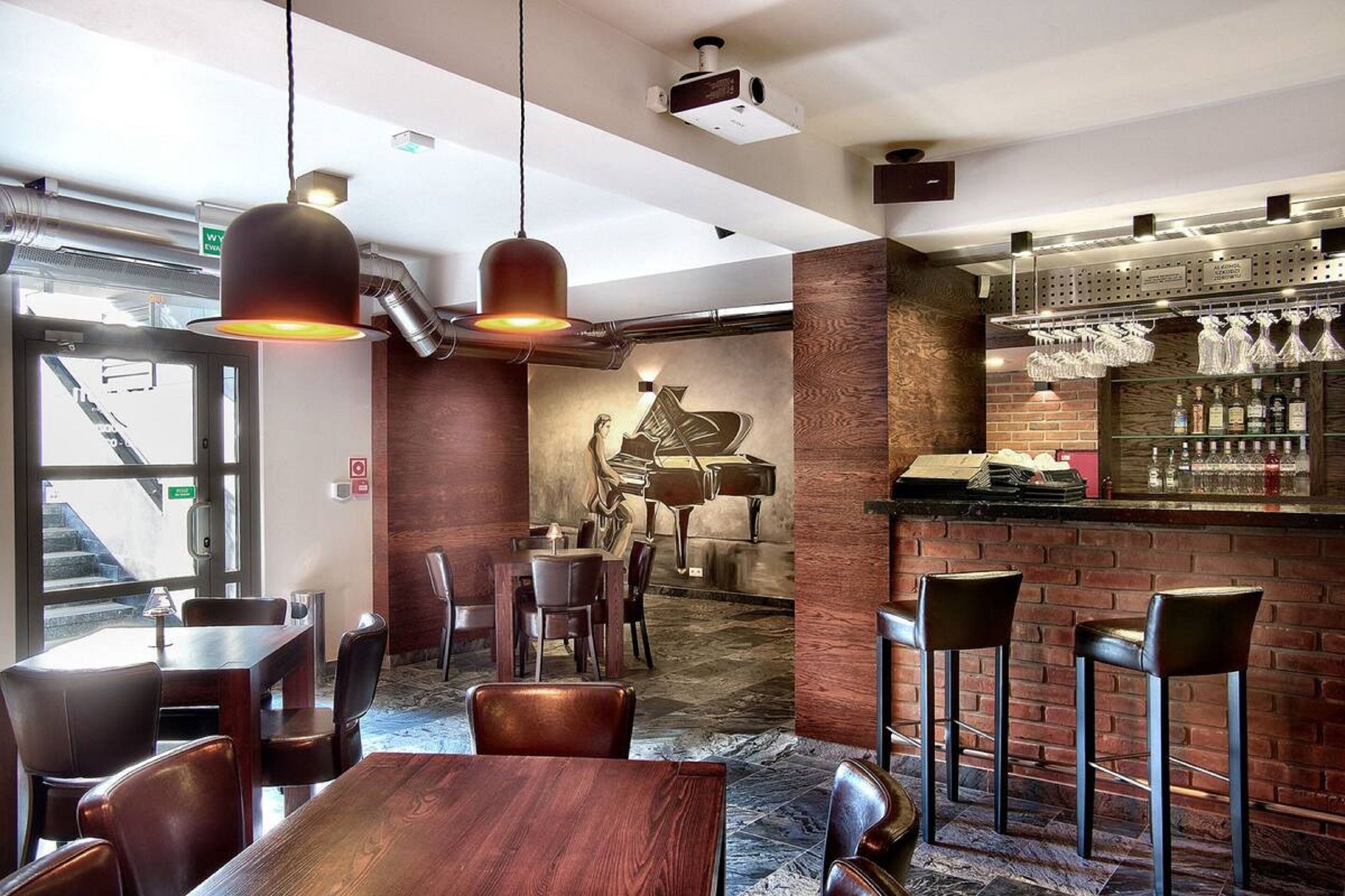 Un restaurante con barra, mesas y sillas de madera, y un mural de un piano en la pared.