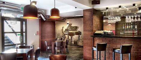 Un restaurante con barra, mesas y sillas de madera, y un mural de un piano en la pared.