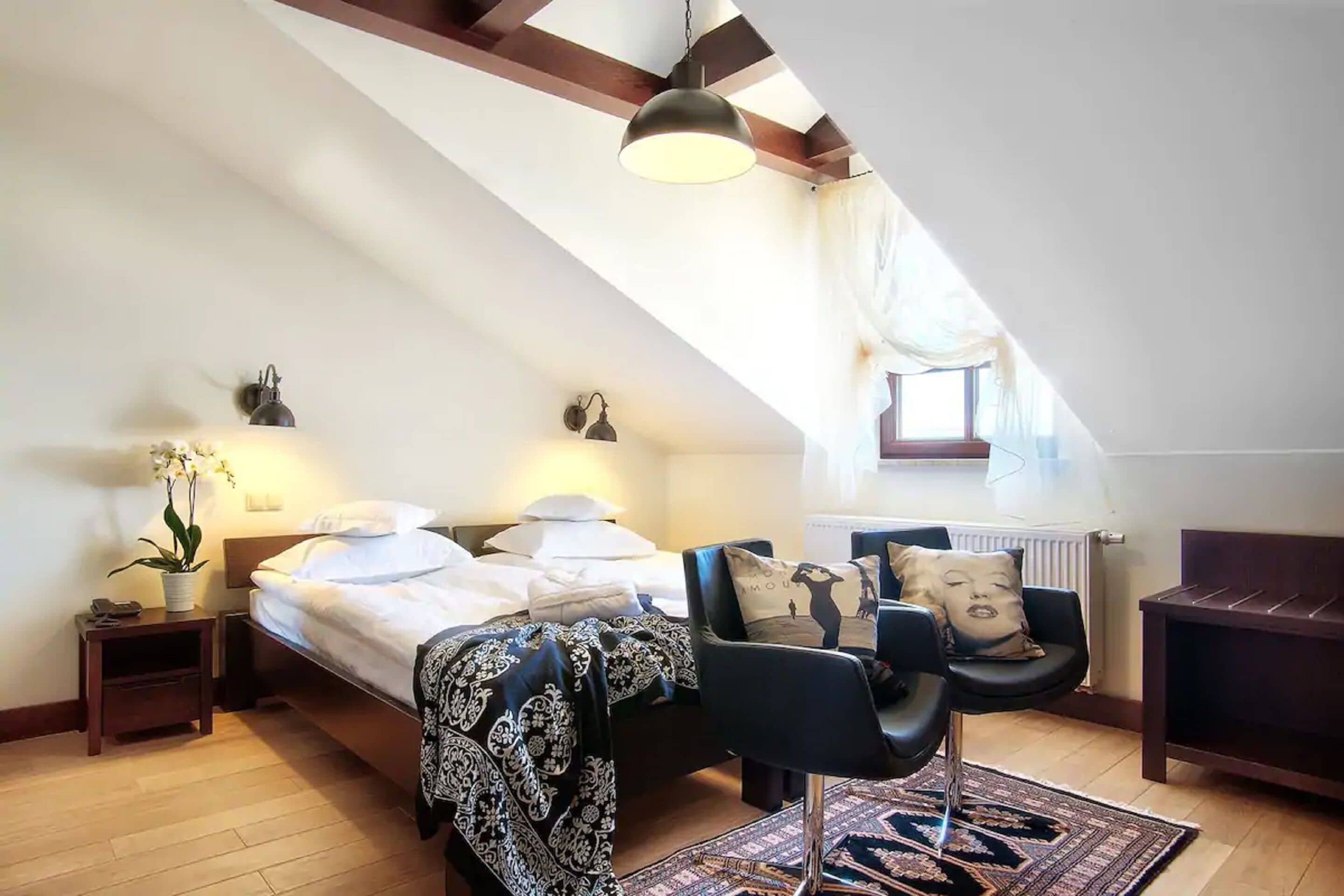 Une chambre à coucher avec un lit, des tables de chevet, une chaise, une lampe et une fenêtre.
