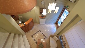 Eine Hotellobby mit einer Rezeption, einem Couchtisch, einer Couch und einer Treppe.