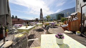 Un patio al aire libre con mesas y sillas, una estatua y vistas a las montañas.