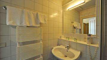 A bathroom with a white sink, a mirror, a towel rack, and a radiator.